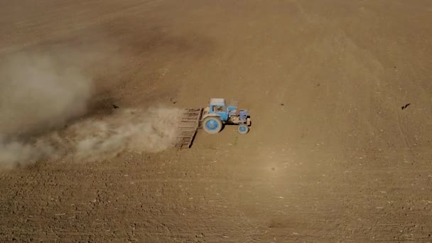 Aerial deslizante atirou agricultor em trator azul arado solo árido empoeirado. Agronegócio na primavera — Vídeo de Stock