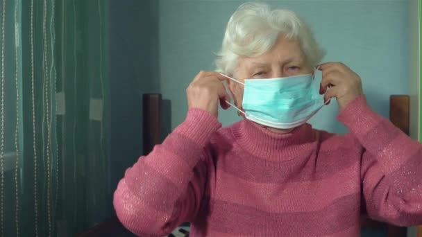 Retrato de anciana abuelita con máscara protectora en la cara en su habitación en casa con iluminación natural — Vídeo de stock