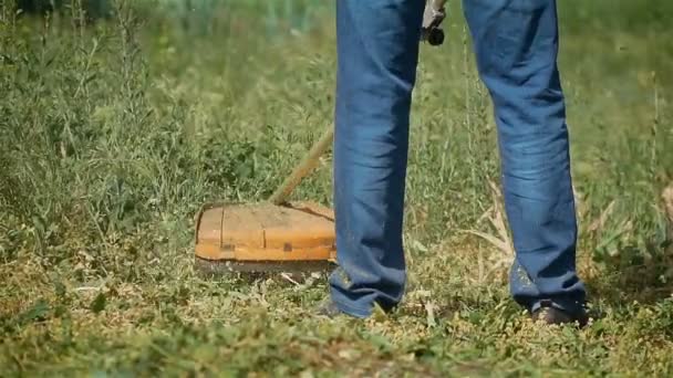 Großaufnahme von Landwirt Gärtner, der Unkraut und Gras in Zeitlupe mit elektrischem Saitentrimmer mäht — Stockvideo