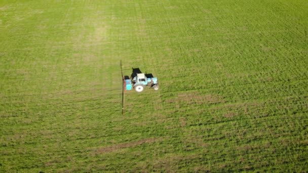 液体化学物質で緑の作物畑を噴霧トラクターに農民のドローン空中ショット — ストック動画