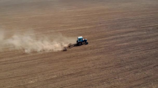 Vue aérienne du tracteur sur champ poussiéreux avec herse à disques préparant le sol pour l'ensemencement 