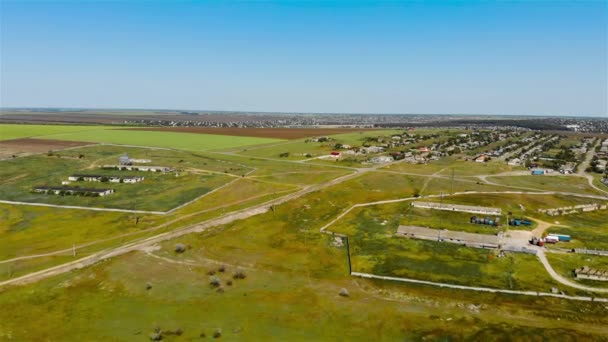 Widok z lotu ptaka z dwoma bazami z wieloma ciężarówkami i kilkoma wioskami wiejskimi w oddali między polami rolniczymi wiosną — Wideo stockowe