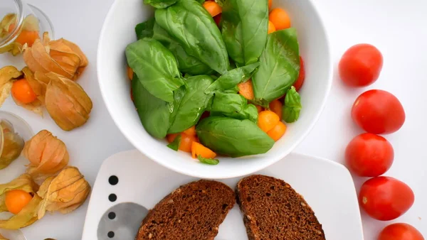 Üst Manzara. Kirazlı domates ve fesleğenli Physalis salatası. Seçici odaklanma. Vejetaryen yemeği. Sağlıklı yaşam tecrübesi. Sebze tarifi. Sebze geçmişi. Organik gıda konsepti. Mutfak yolculuğu - Physalis & Letonya ekmeği. 