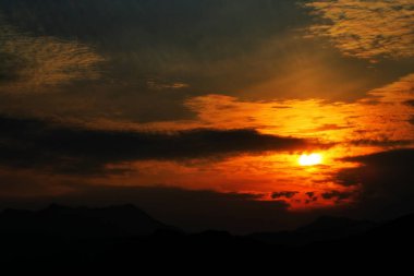 Dağların üzerinde bulutların arasında gün batımı