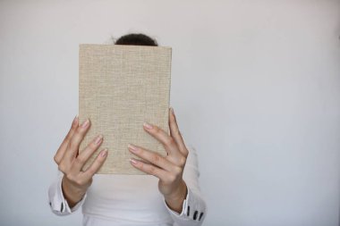 Genç bir kız elinde bir kitap tutuyor.