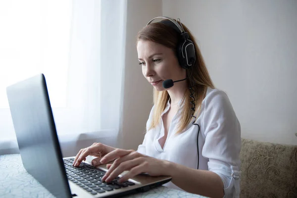 Genç Amerikalı kız kulaklık takıyor ve laptoptan arıyor. Güzel bayan öğrenci bilgisayar ekranına bakıyor webinar izliyor ya da webcam ile görüntülü sohbet yapıyor..