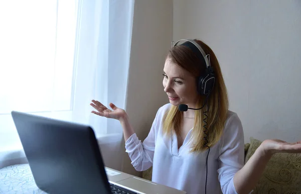Genç Amerikalı kız kulaklık takıyor ve laptoptan arıyor. Güzel bayan öğrenci bilgisayar ekranına bakıyor webinar izliyor ya da webcam ile görüntülü sohbet yapıyor..