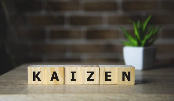 Kaizen gelişme tabelası parlak bir odadaki ahşap bir masanın üzerindeki bloklardan yapılmış..