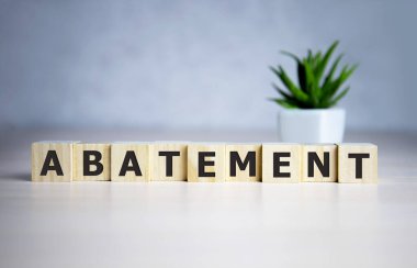 Ahşap küplere mavi arka plan üzerine yazılmış ABATEMENT kelimesi.