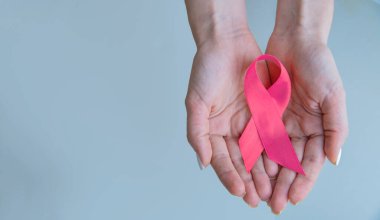 Sağlık ve tıp konsepti - kız elleri pembe meme kanseri farkındalığı kurdelesi tutuyor.