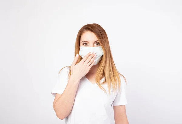 Stock image Beautiful caucasian young woman in white t-shirt with disposable face mask. Protection versus viruses and infection. Studio portrait, concept with white background. covers his mouth with his hand.