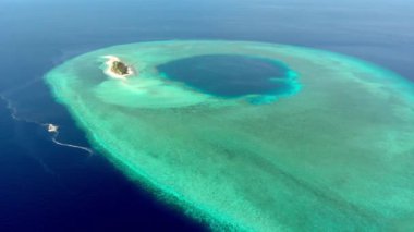 Endonezya 'daki Wakatobi Ulusal Parkı' nda cennet gibi bir mercan adasının üzerinde uçuyor.