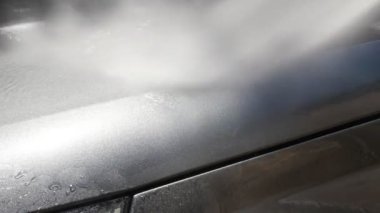 Gri renkli kaput, otomatik oto yıkama makinesiyle yıkanır.