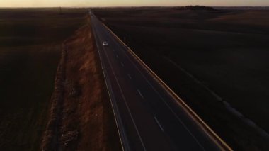 Gün batımında otoyol, polis arabası, polis yolları kontrol ediyor. 
