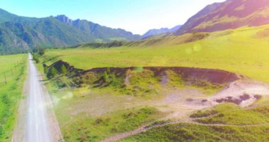 Güneşli yaz sabahında havadan kırsal dağ yolu ve çayır. Asfalt karayolu ve nehir 