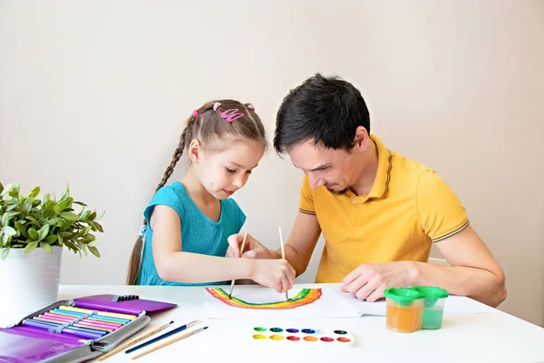 Baba ve kızı birlikte bir gökkuşağı çiziyor. Baba ve çocuk çizim yaparken eğleniyorlar. Mutlu bir aile. Sevdiklerinle daha çok vakit geçirmek.