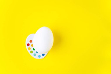 Sarı arkaplanda çocuk renk paleti üzerine beyaz yumurta ve kopya alanı
