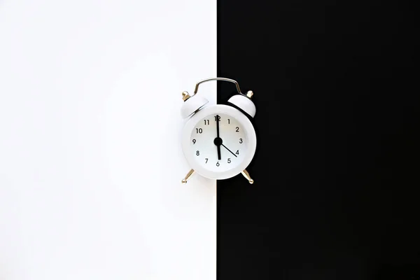 Alarm clock on black and white background. White vintage alarm clock on a minimalistic background with copy space.  Minimal thing. Minimal think