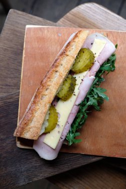 Jambonlu, salatalık turşulu ve ahşap arka planda peynirli enfes kırsal baget sandviç.