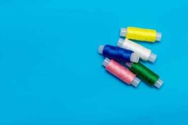 Mavi arka planda beyaz renkler, makas açık, ve turkuaz kurdele dikmek için, beyaz, mavi, yeşil, pembe, sarı iplik mavi arkaplanda, kopyalama alanı, üst görünüm