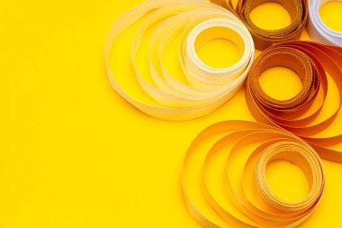 Sarı arkaplanda çok renkli kıvrımlı kurdele, üst görünüm, doku