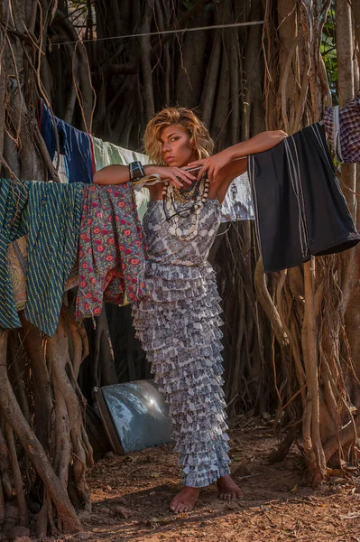 Çamaşır arka planında poz veren eski bir banyan ağacının arka planındaki güzel elbiseli kız..