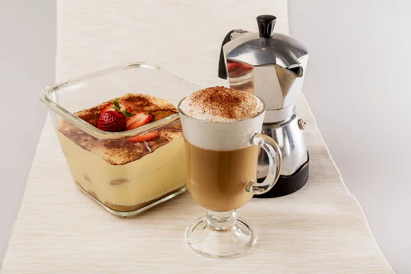 İrlanda bardağında sütlü kahve, cam kutuda tiramisu ve kahve demliği.