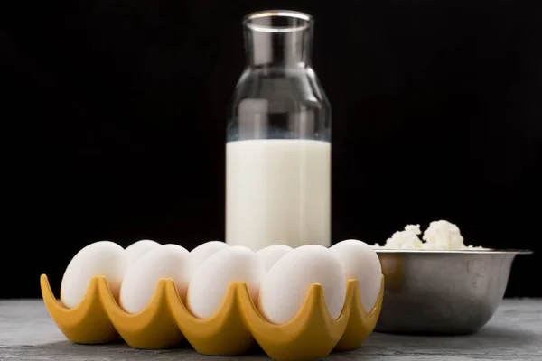 Siyah arka planda kahvaltı için süt, yumurta ve süzme peynir.