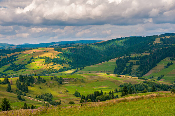 Panorama Carpathian mountain summer landscape with blue cloudy sky, agriculture fields and countryside roads