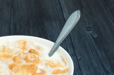 Müsli ile sağlıklı vejetaryen kahvaltı. Ahşap masa üzerinde taraftan görüntüleyin. Beyaz kase sütlü Mısır gevreği.