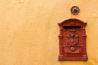 Sarı duvardaki kırmızı posta kutusu.