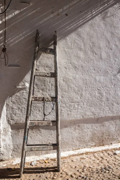 Oude houten ladder en een muur in zonlicht — Stockfoto