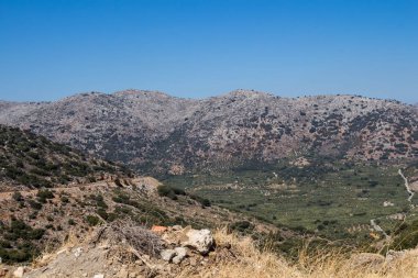 Kayalık dağlar, zeytin ağaçları ve çeşitli bitkilerle dolu vadiler. Sonbaharda mavi gökyüzü güneşli olacak. Merkez Girit, Yunanistan.