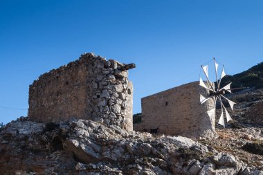 Taştan yapılmış yel değirmenleri, Pinakaino, Lasithi Platosu 'ndaki bir tepede. Parlak mavi gökyüzü. Girit, Yunanistan.