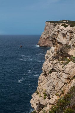 Adanın batı kıyısındaki kayalıkların vahşi yüzeyi Park Parco Naturale di Porto Conte 'de. Akdeniz 'in ışık dalgaları. Mavi gökyüzü. Capo Caccia, Sardinya, İtalya.