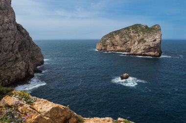 Açık beyaz bulutlu mavi gökyüzü ile bahar günü. Doğal park Parco Naturale di Porto Conte 'nin Akdeniz' deki Isola Forada 'daki görüntüsü. Sardunya, İtalya.