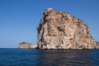 Akdeniz 'in sakin mavi suları, Capo Caccia yarımadasını çevreleyen uçurumun tepesinde beyaz bir bina. Parlak mavi gökyüzü. Sardunya, İtalya.
