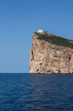 Akdeniz 'in sakin mavi suları, Capo Caccia yarımadasını çevreleyen uçurumun tepesinde beyaz bir bina. Parlak mavi gökyüzü. Sardunya, İtalya.