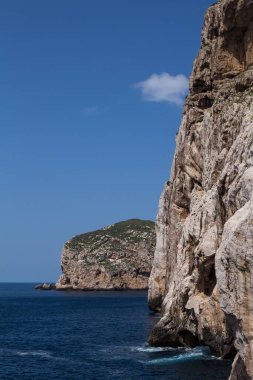 Akdeniz 'in koyu mavi suları, Capo Caccia' nın kayalık uçurumları ve Isola Forada adası. Mavi gökyüzü.