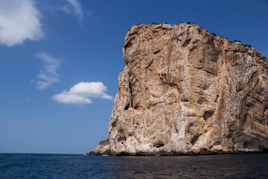 Capo Caccia yarımadasını çevreleyen Akdeniz 'in sakin mavi suları. Mavi gökyüzünde küçük bulutlar. Sardunya, İtalya.
