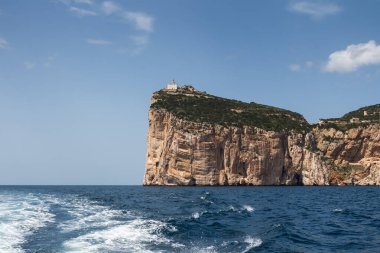 Capo Caccia yarımadasını çevreleyen Akdeniz 'in sakin mavi suları. Mavi gökyüzünde küçük bulutlar. Sardunya, İtalya.