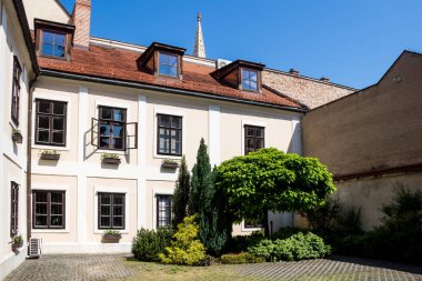 Şehir merkezinde yenilenmiş bir tarihi binanın avlusunda. Ağaçlar ve çalılar. Parlak mavi gökyüzü. Bratislava, Slovakya.