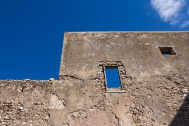 Ön cephesi olmayan duvarlar ve pencere yerine delikler. Terk edilmiş evin kalıntıları. Parlak mavi gökyüzü. Dar Caid Hacı (aynı zamanda Hoca olarak da bilinir), Fas.
