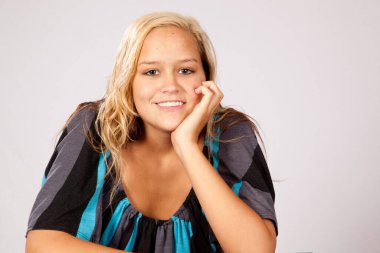 Güzel sarışın, gülümseyen ve yüzünde elleri olan.