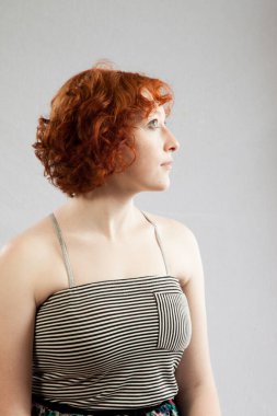 Düşünceli kızıl saçlı kadın düşünceli görünüyor.