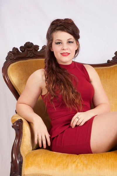 Mulher Encantadora Vestido Vermelho Sentado Sofá Ouro — Fotografia de Stock