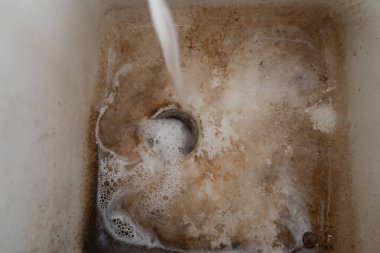 Dirty sink with water flowing the dirt is stuck at the bottom clipart