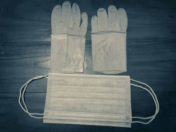 一双橡胶医用手套 木制桌子上的外科口罩 — 图库照片