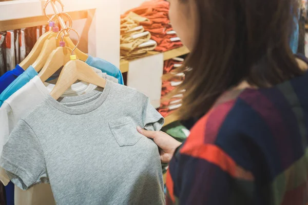 Young asian woman shopping trendy kid clothes for her\'s son in shopping mall, Selective focus.