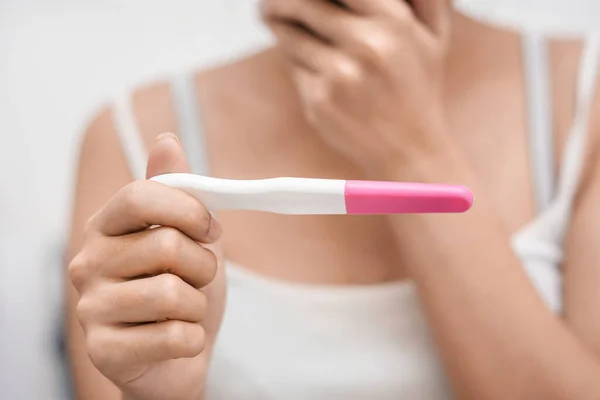 Hamilelik testi tutan Asyalı genç bir kadın ve banyosu, sağlığı ve sağlıklı konsepti, kısırlık sorunu, seçici odaklanma sorunu sonucu şok olmuş..